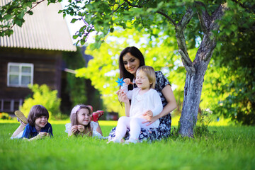 Fototapeta premium Young large family on a summer morning walk. Beautiful mother with children is playing in the park.