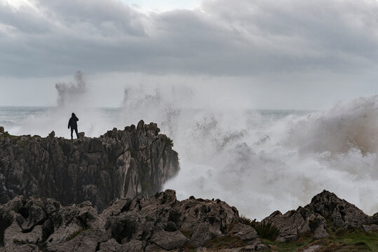 Distant male taking photo of stormy waves  - Powered by Adobe