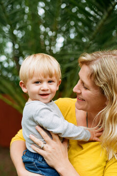Loving mom holding young blond son in backyard