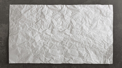 Old and crumpled sheet of paper on a vintage black background.