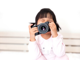 Little oriental girl taking a photo with a mirrorless single