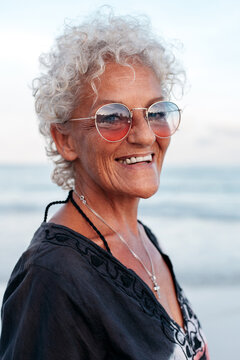 Smiling elderly woman in sunglasses on beach