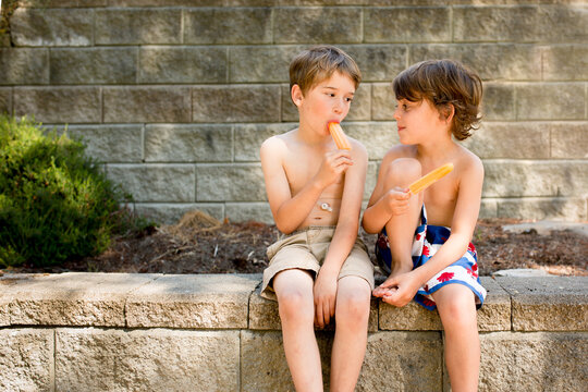 Boys eating popsicles look at one another 