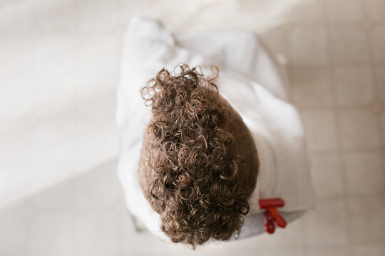 Child with curly mohawk sits wrapped in towel