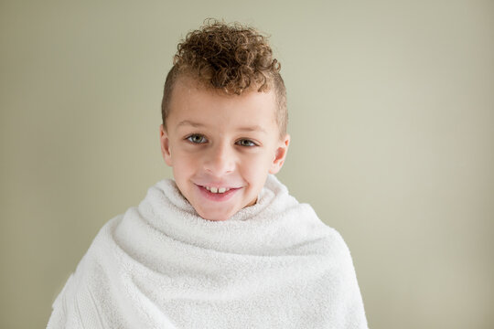 Brinnign boy with curly mohawk wrapped in towel