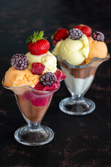 Ice cream in glass bowl. Ice creams on dark background. Milk, chocolate, cherry, melon and caramel ice cream.