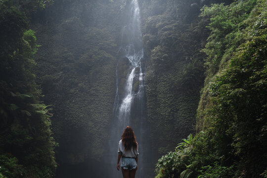 Tourist woman explore waterfall in a jungle