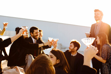 Happy coworkers with glasses of wine celebrating festive occasion outdoors