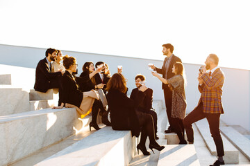 Stylish colleagues with wine celebrating festive occasion on stairs