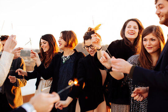 Crop glad partners with Bengal lights during party on rooftop