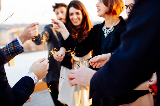 Crop happy partners with sparklers during party in sunlight outdoors