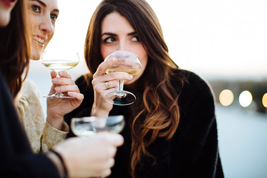 Crop women drinking wine during party on rooftop