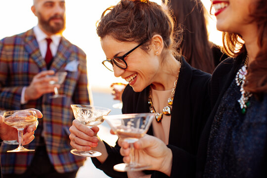 Crop happy coworkers with alcoholic drinks celebrating festive occasion outdoors