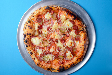 Pizza with bavarian sausages, Mozzarella cheese, onion and cucumbers isolated on blue background.