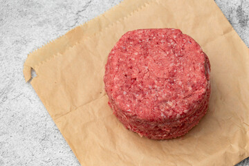 Raw beef burgers stacked on a brown paper bag. Environmentally friendly packaging for recycling