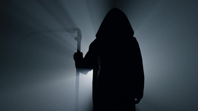 Silhouette grim reaper waiting with scythe indoors. Scytheman standing darkness.