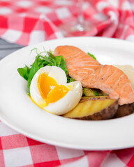 Salmon steak with fresh greenery and boiled eggs served on a white plate. Healthy food concept