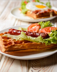 Waffle wholesome breakfast. Sour waffles with grilled sausages, fried eggs, delicious sauce and fresh vegetables.