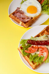 Waffle wholesome breakfast. Sour waffles with grilled sausages, fried eggs, delicious sauce and fresh vegetables.