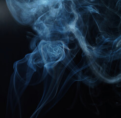 Flowing patterns of smoke from burning isolated black background.