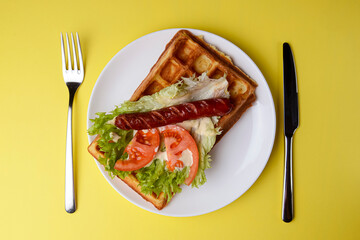 Waffle wholesome breakfast. Sour waffles with grilled sausages, delicious sauce and fresh vegetables.