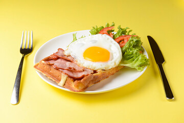 Fototapeta na wymiar Waffle wholesome breakfast. Sour waffles with fried eggs, delicious sauce and fresh vegetables.