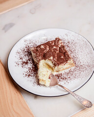 Traditional Tiramisu Cake served on a white plate over wooden background. Italian French cuisine concept
