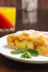 Slice of delicious fresh baked Rustic Apple Pie served on a white plate on wooden table background.
