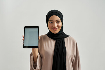 Happy arabic woman demonstrating empty tablet screen