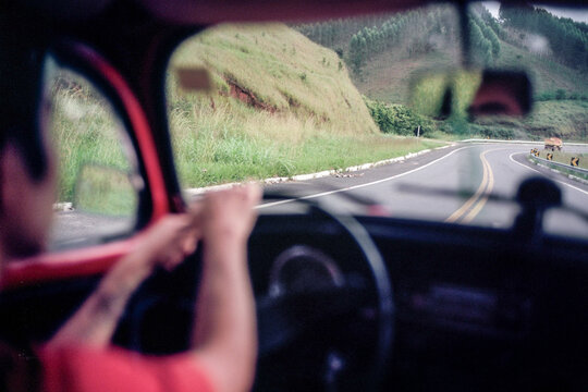 Fototapeta Point of view of a man driving a red vintage car in the mountains