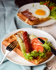 Waffle wholesome breakfast. Sour waffles with grilled sausages, fried eggs, delicious sauce and fresh vegetables.