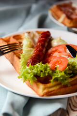 Waffle wholesome breakfast. Sour waffles with grilled sausages, delicious sauce and fresh vegetables.
