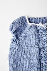 blue knitted product on knitting needles on a white background