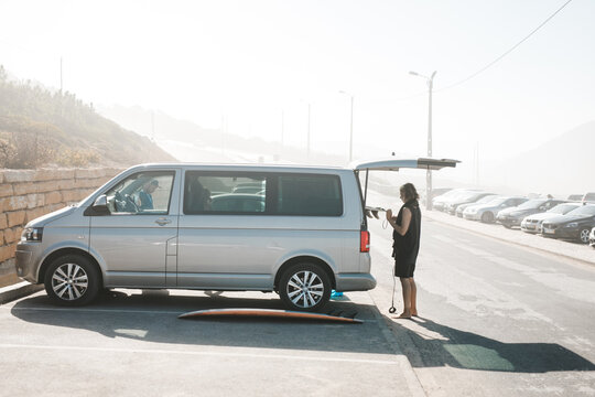 Young man taking surfboard out of car

