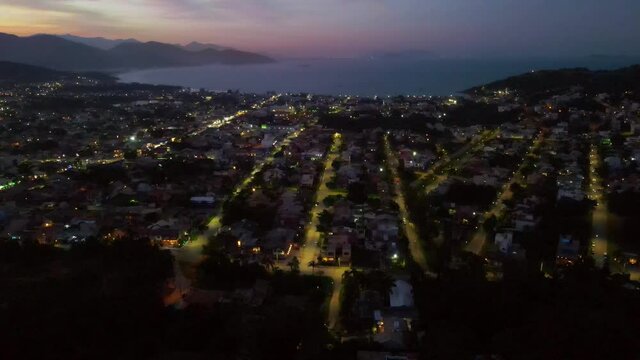 Aerial View of a city with small buildings and beach at sunset. Drone Footage.