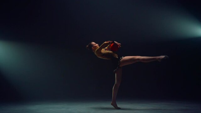Flexible woman performing with ball. Beautiful girl doing rhythmic gymnastics.