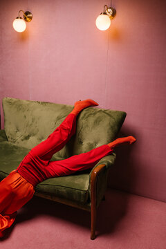 woman with red clothes in a pink room with on a green couch