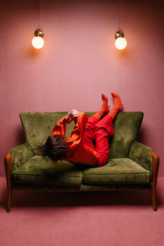 woman with red clothes in a pink room with on a green couch