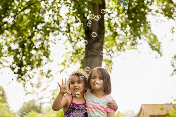 cute mutiracial girls grab at bubbles