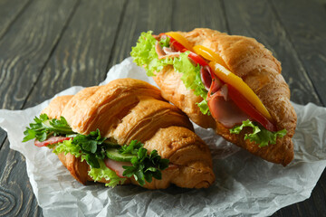 Tasty croissant sandwiches on wooden background, close up