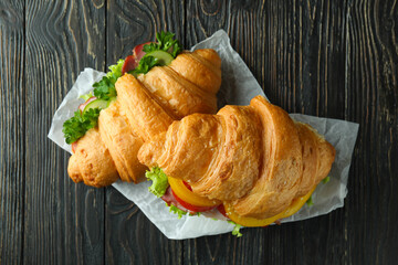 Tasty croissant sandwiches on wooden background, top view