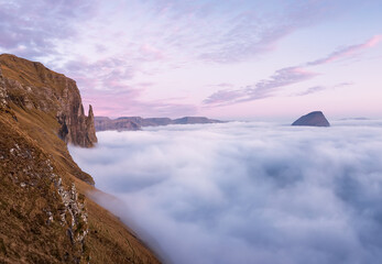  Rock "Witch's Finger" Trøllkonufingur at sunset. Clouds covered the Atlantic Ocean. Faroe Islands, Europe. Aerial view