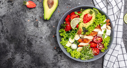 Ketogenic, keto or paleo diet lunch bowl with grilled chicken and avocado, feta cheese, quail eggs, strawberries, nuts and lettuce. Healthy food trend. Top view