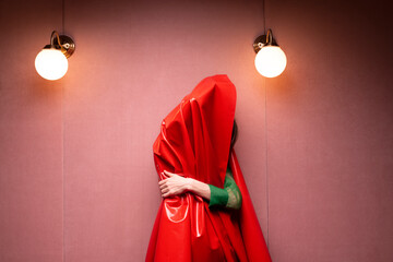 woman covered with red shiny fabric in a pink room