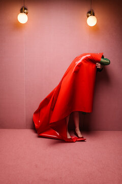 woman covered with red shiny fabric in a pink room
