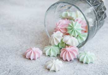 Small white, pink and green meringues in the glass