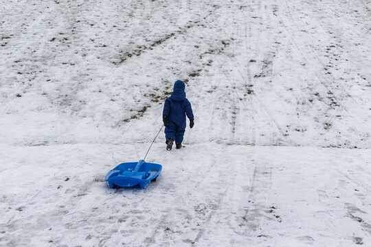 A boy pulls a toboggan across a field