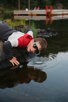 Boy looking in lake water with goggles