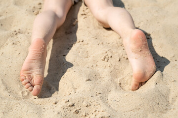 Children's legs in the sand on the beach on summer day