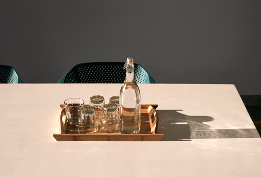 Water bottles and glasses with water on a clean and tidy table in the afternoon sun